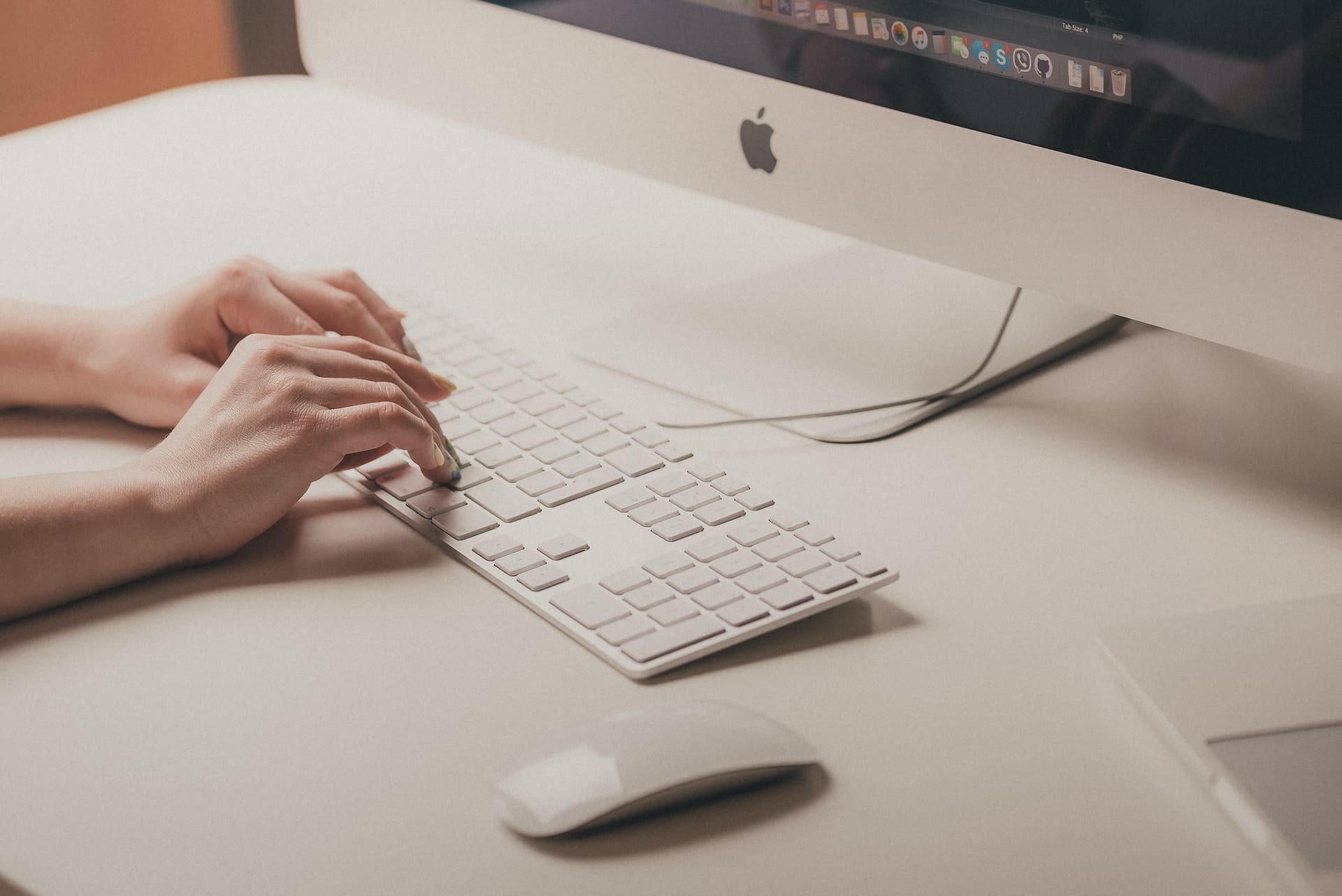 a person typing in white keyboard with imac