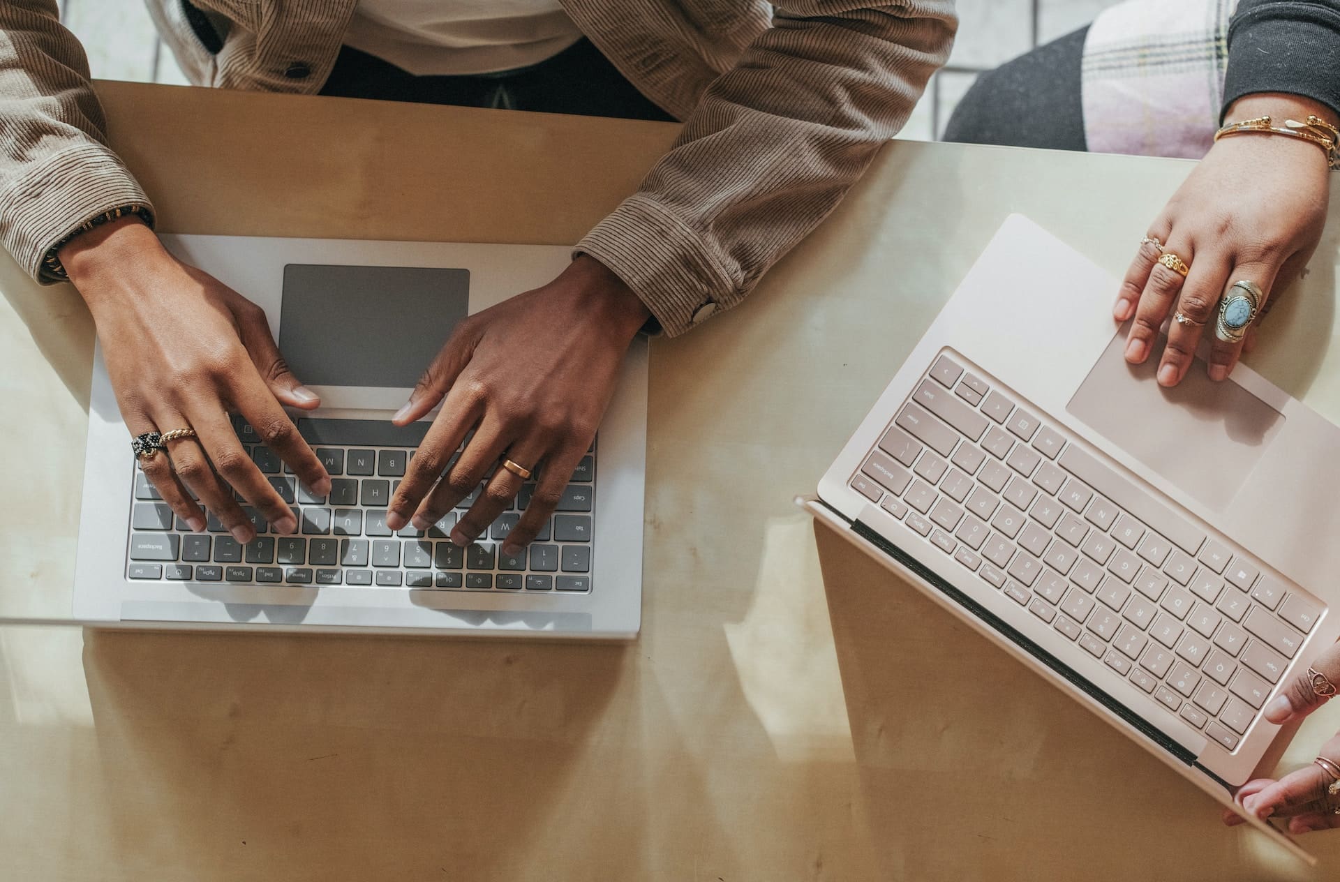 2 persons typing using laptop