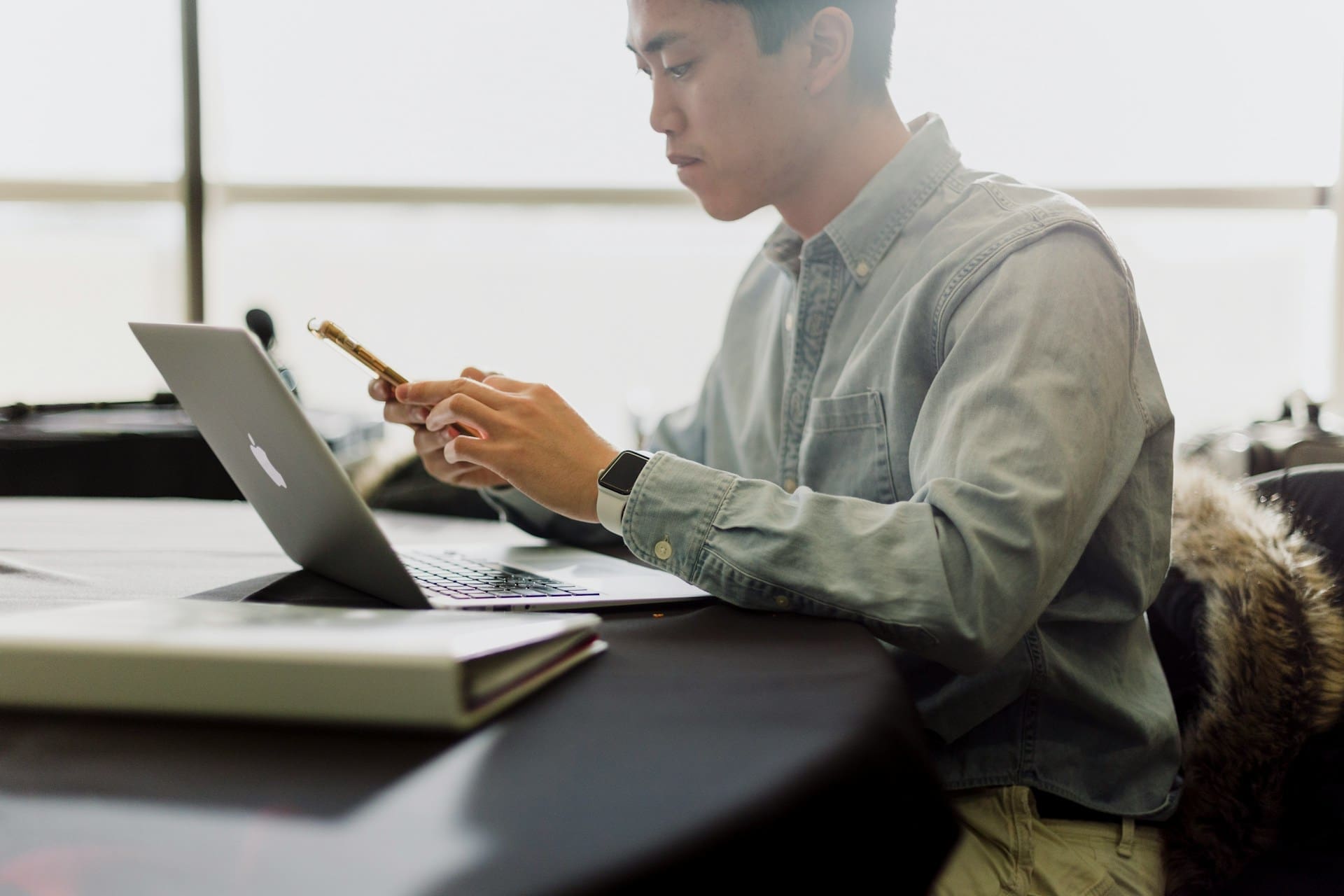 a man using a mobile phone in front of a laptop