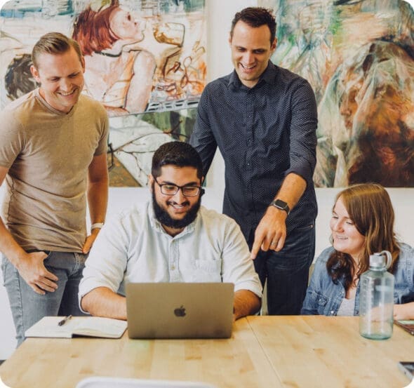 Hey Reliable Web Development Agency - Professionals standing around laptop computer smiling
